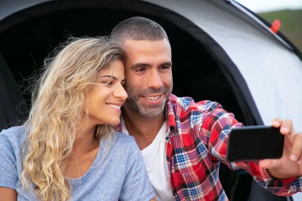 A happy couple enjoying a camping trip and capturing a selfie together.