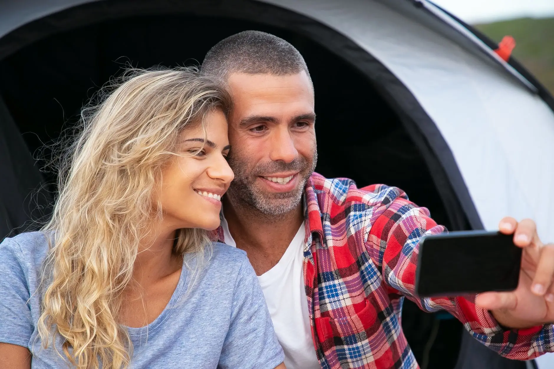 A happy couple enjoying a camping trip and capturing a selfie together.