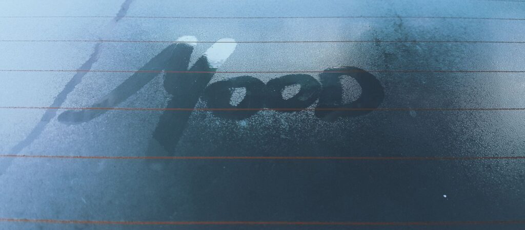 Moist car window with 'mood' written in fog, evoking a contemplative atmosphere.