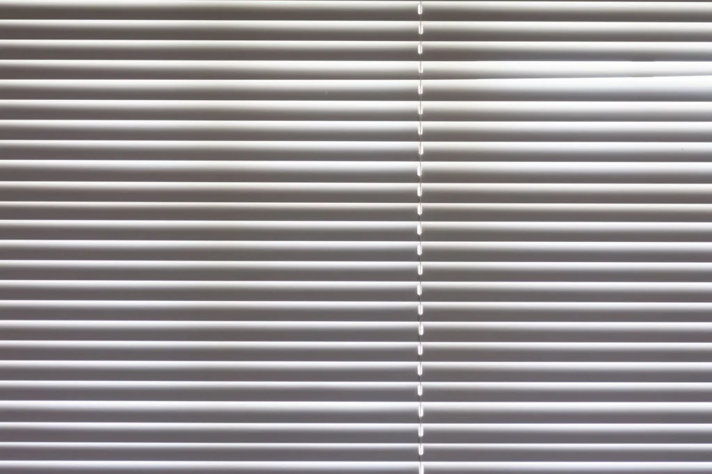 Close-up of horizontal window blinds indoors with natural light highlighting texture.