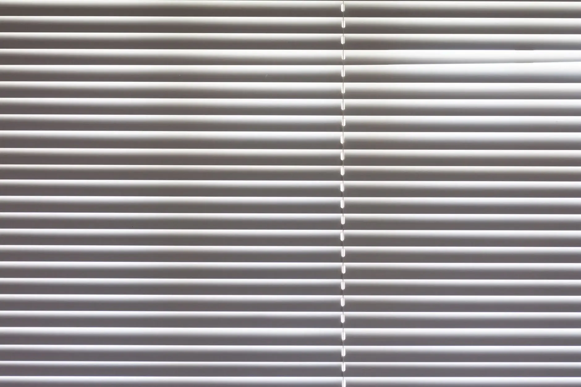 Close-up of horizontal window blinds indoors with natural light highlighting texture.