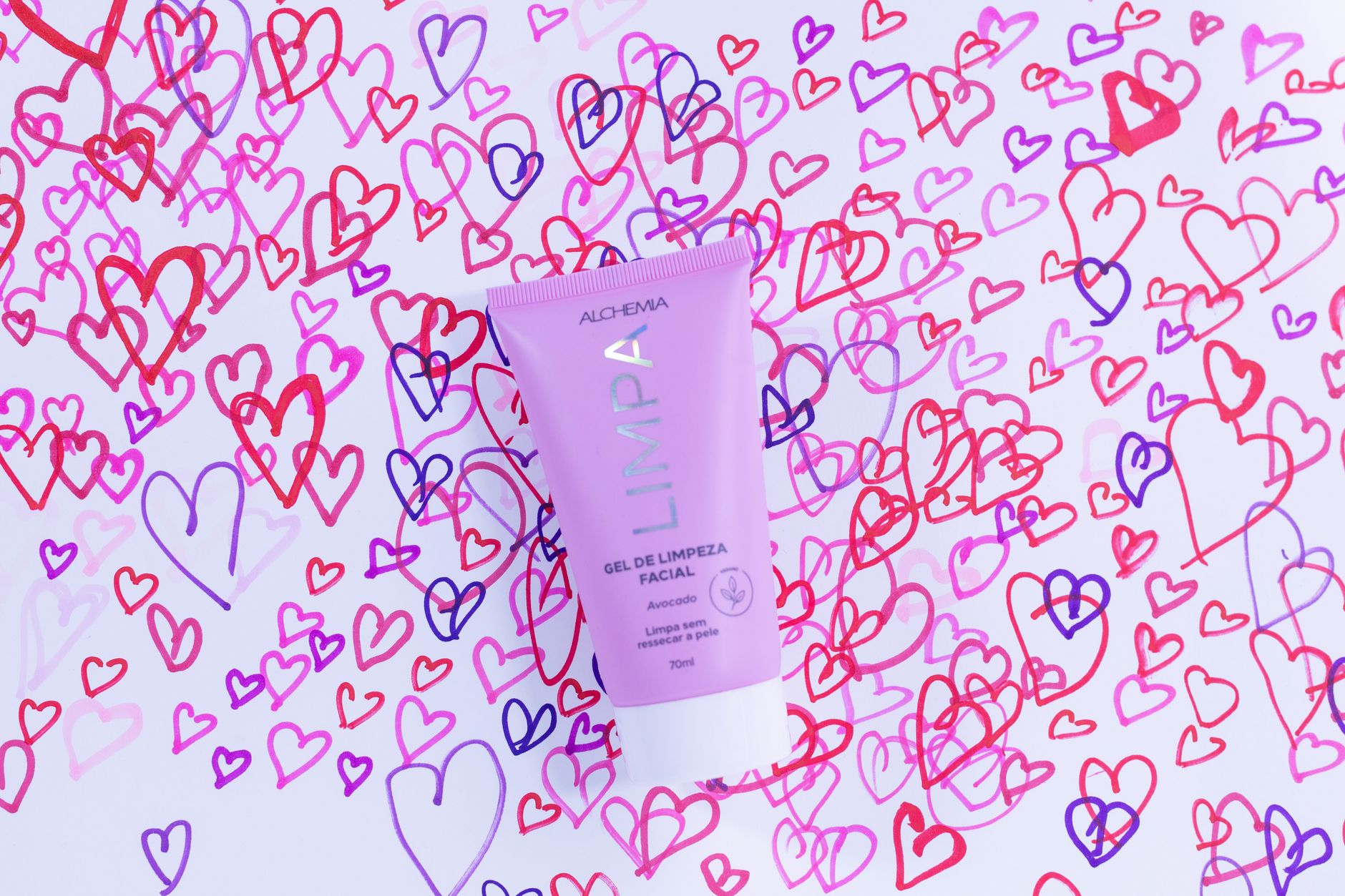 Pink facial cleansing gel tube surrounded by colorful heart doodles on white background.