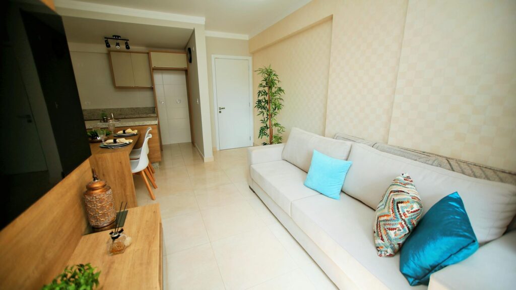 Spacious modern living room with a white couch, blue pillows, and a compact dining area.