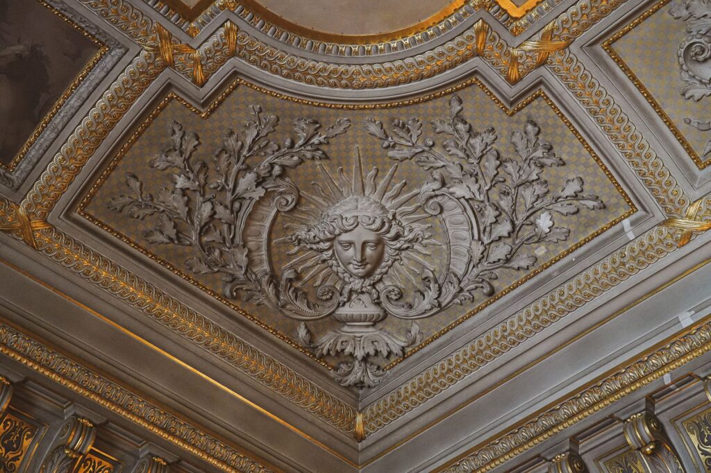 Intricate baroque ceiling design with ornate gold and historical motifs in a French castle.