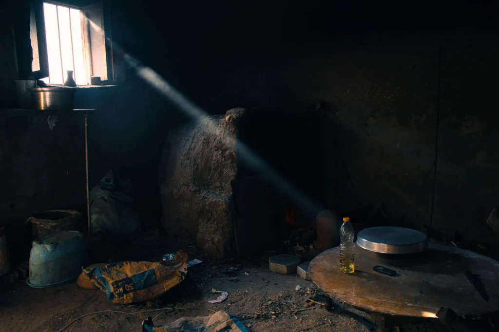 A sunbeam highlights a rustic, cluttered interior room, adding dramatic contrast.