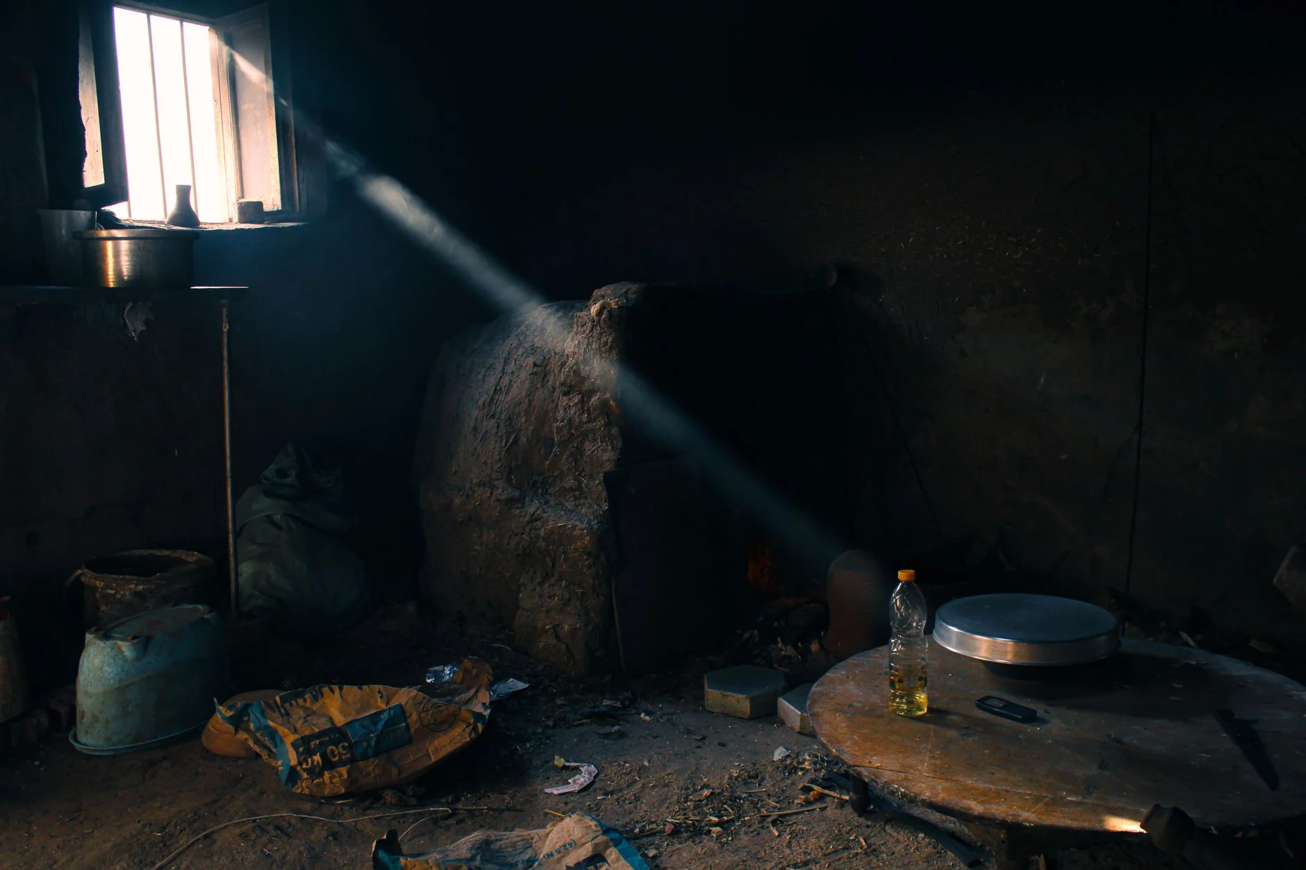 A sunbeam highlights a rustic, cluttered interior room, adding dramatic contrast.