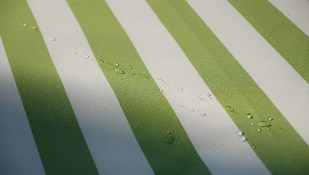 Green and white striped fabric with translucent water droplets, showcasing texture and detail.