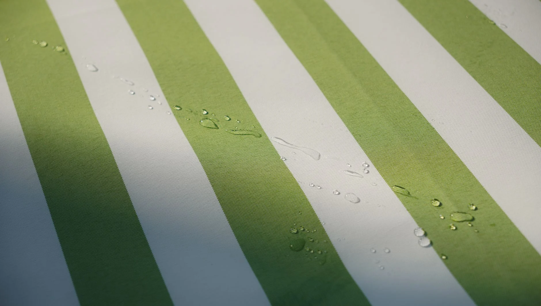 Green and white striped fabric with translucent water droplets, showcasing texture and detail.