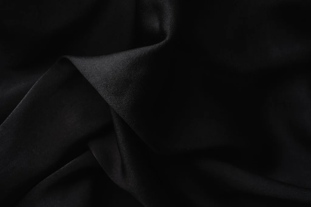 Close-up of luxurious black fabric with soft, elegant folds creating a textured appearance.