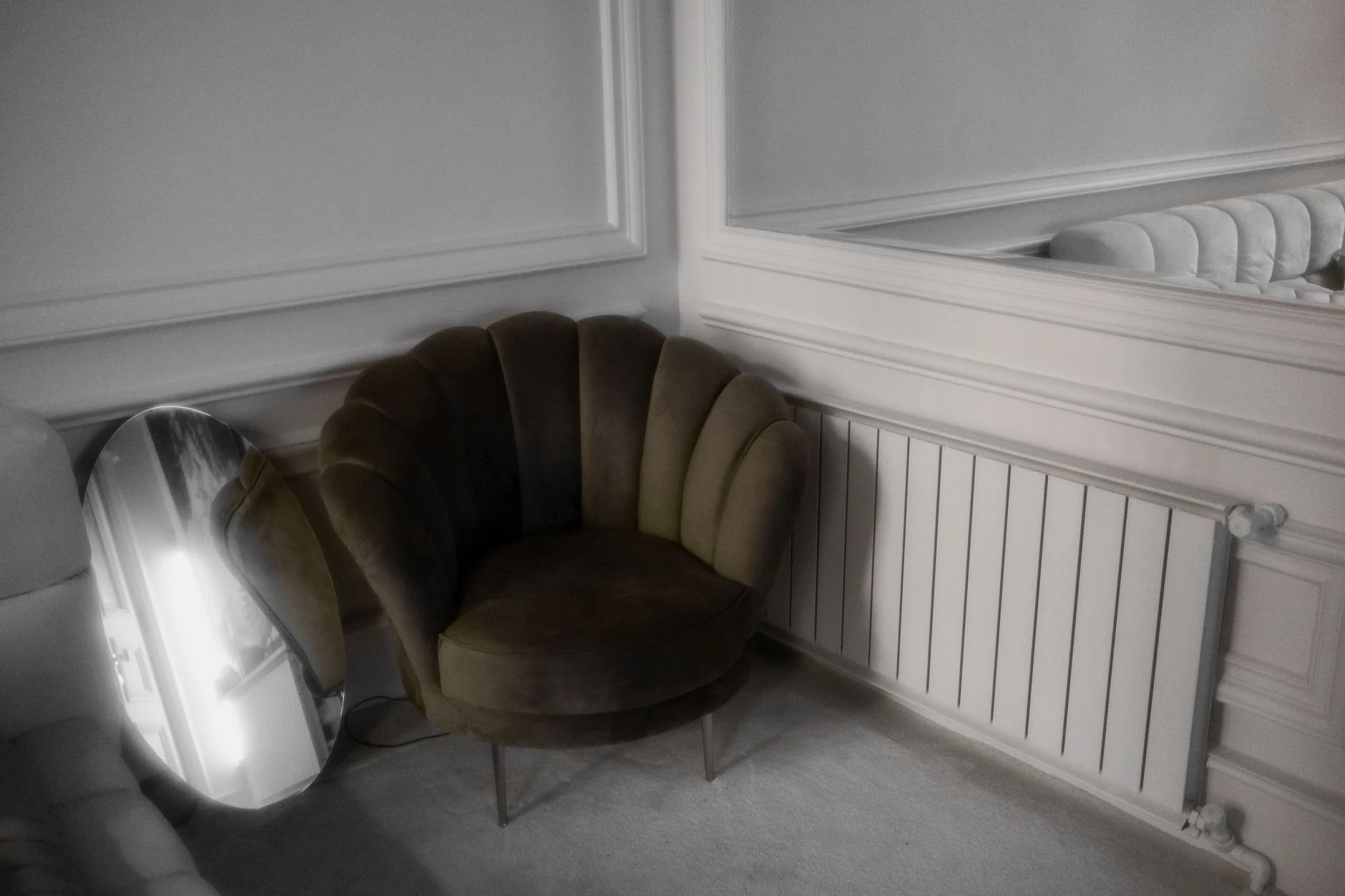 A stylish room featuring a modern armchair and decorative mirror reflecting its sophisticated decor.