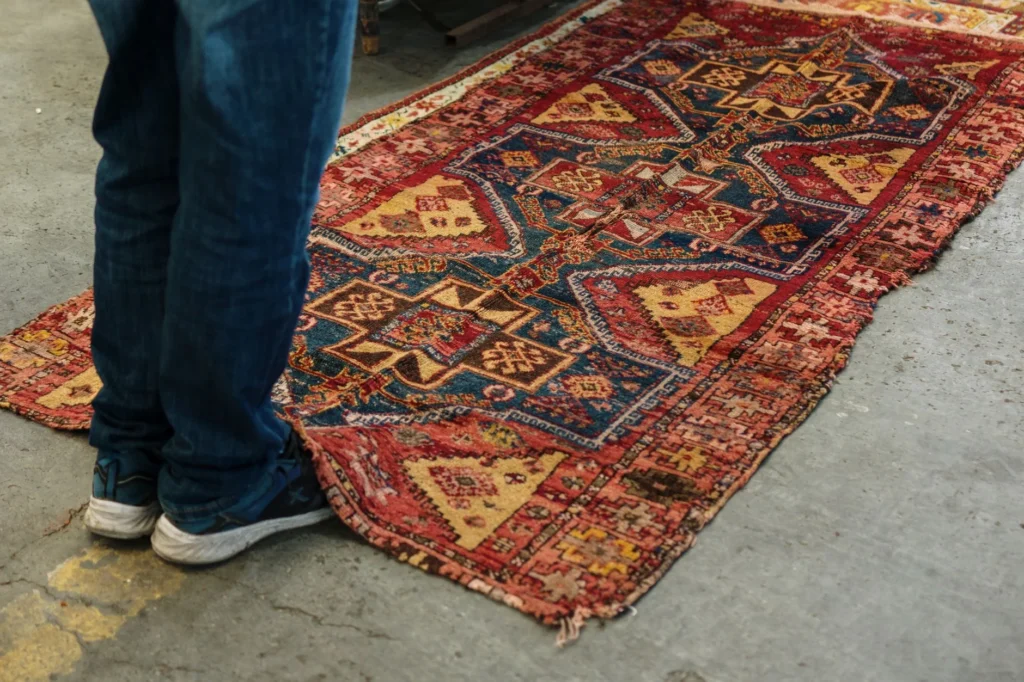 A vibrant vintage Persian rug with intricate geometric patterns on a concrete floor.