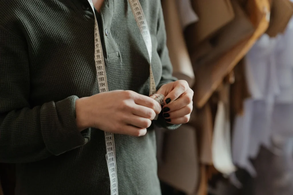 Close-up of a person using a measuring tape in a sewing studio, focusing on patterns and precision.