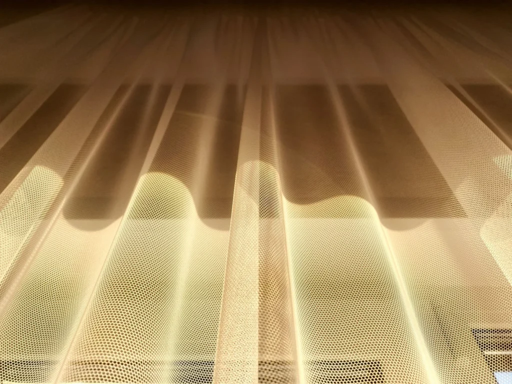 A low-angle shot of golden sheer curtains beautifully illuminated by sunlight.
