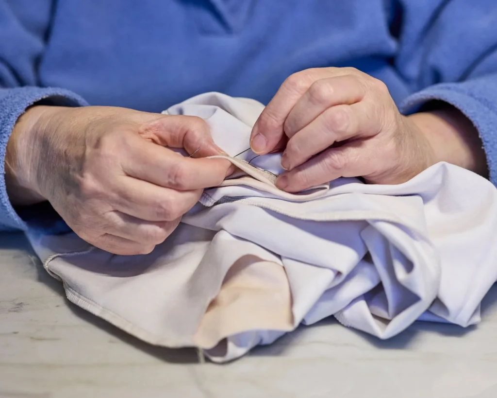 Detailed image of hands sewing white fabric, showcasing precision and skill in a traditional craft.