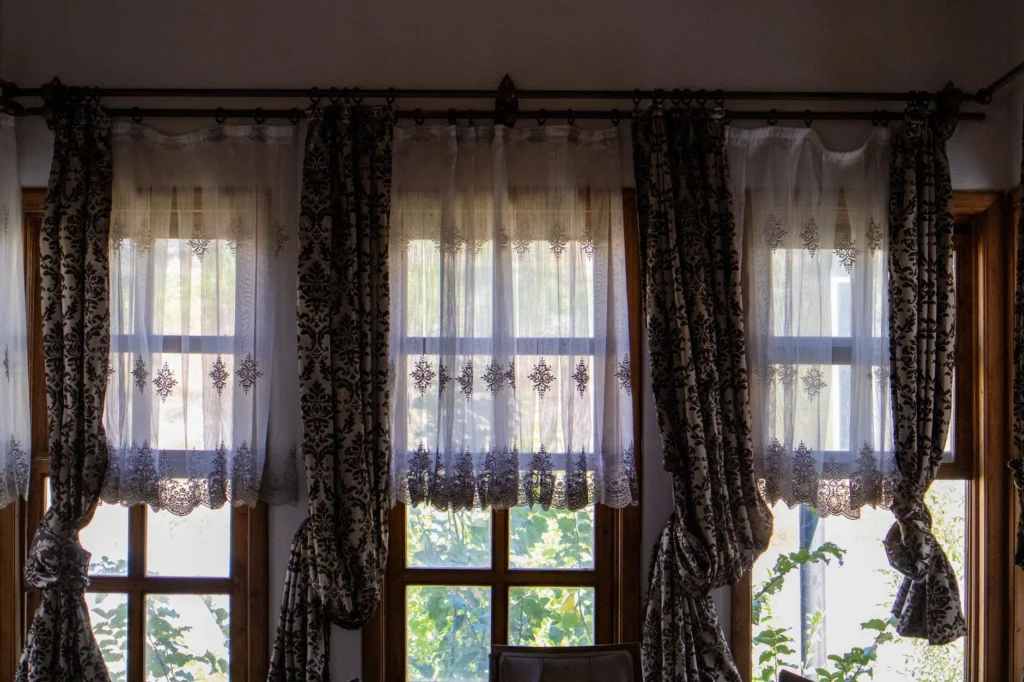 Sunlit room with elegant traditional curtains overlooking a garden view.