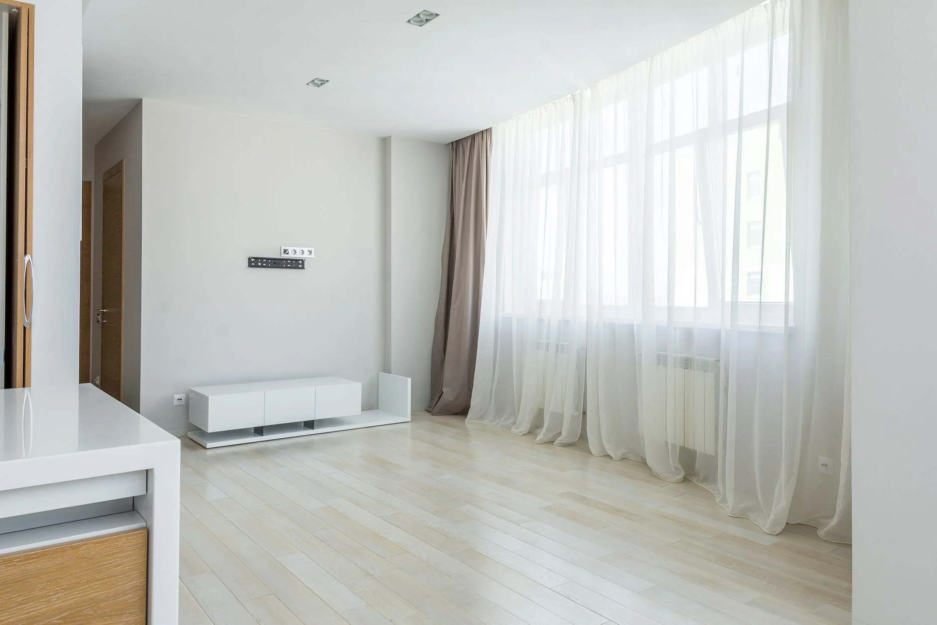 Bright modern minimalist apartment interior with large windows and sheer curtains.