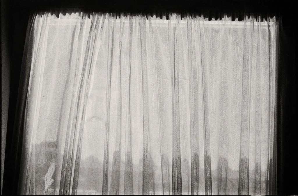 Black and white photo of sheer curtains with a sense of mystery and subtle lighting.