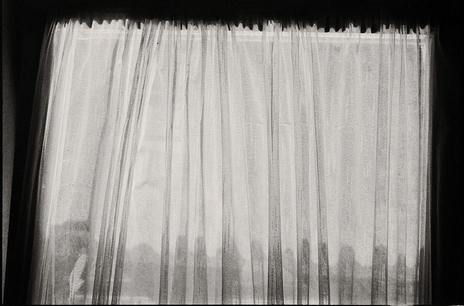 Black and white photo of sheer curtains with a sense of mystery and subtle lighting.