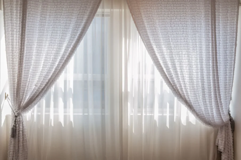 Sun shining through elegant white curtains in a cozy, modern interior setting.