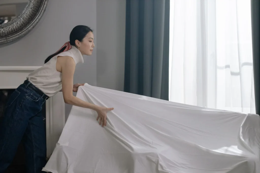 Woman adjusting white curtains indoors, enhancing room decor.