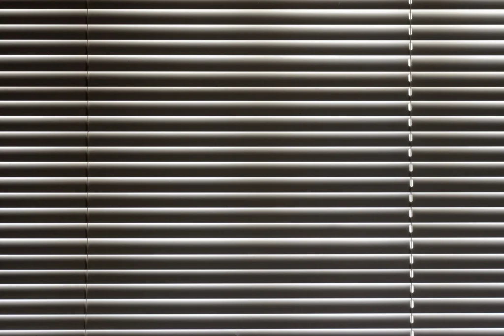 Minimalist close-up of sleek horizontal window blinds with metallic sheen.