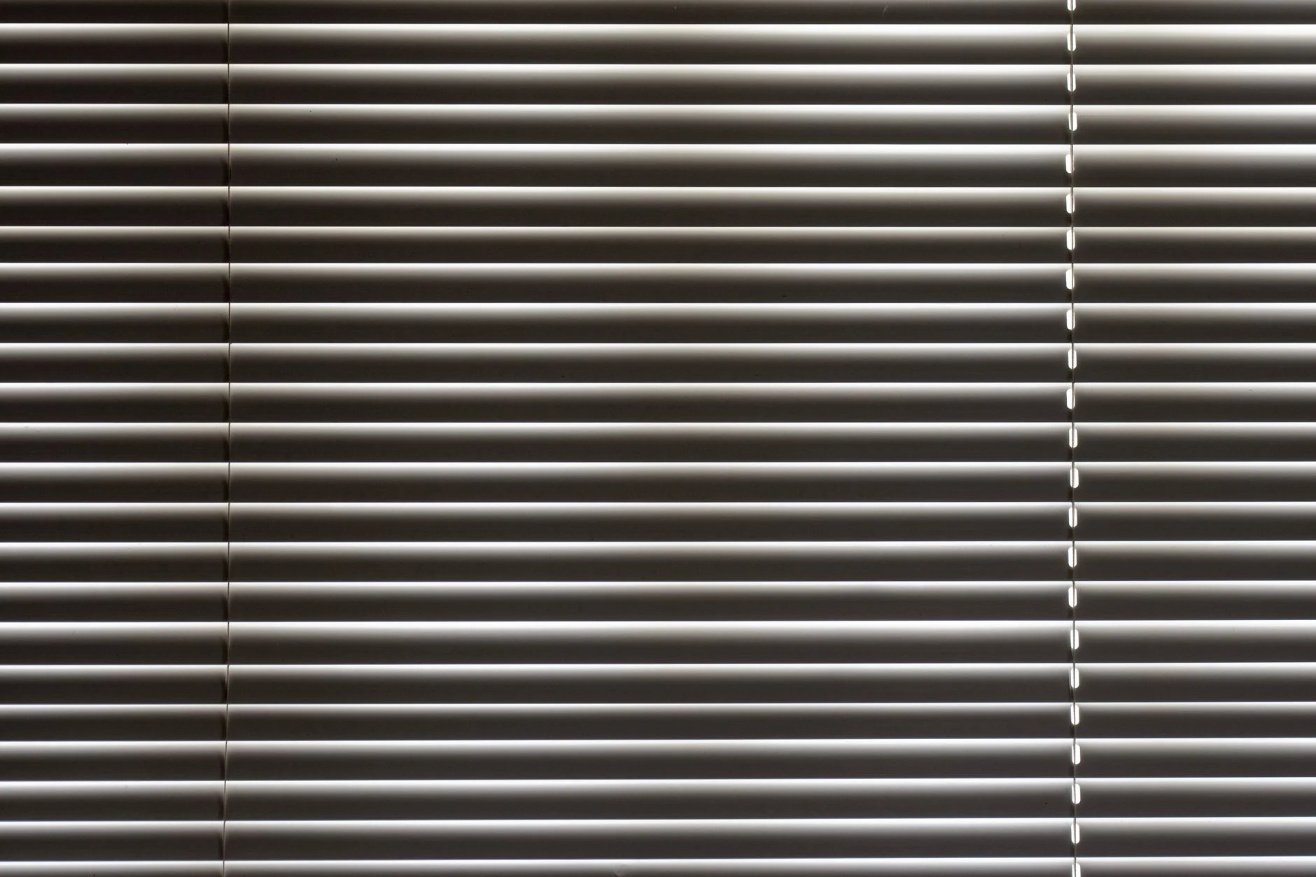 Minimalist close-up of sleek horizontal window blinds with metallic sheen.