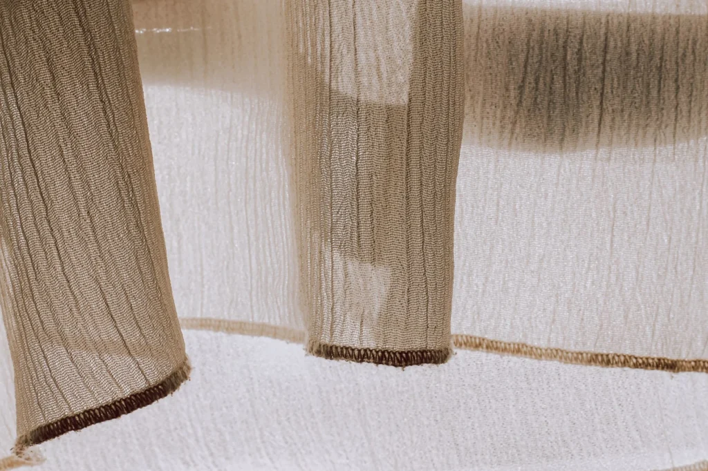 Close-up of sheer fabric with sunlight creating delicate shadows and textures, perfect for textile design.