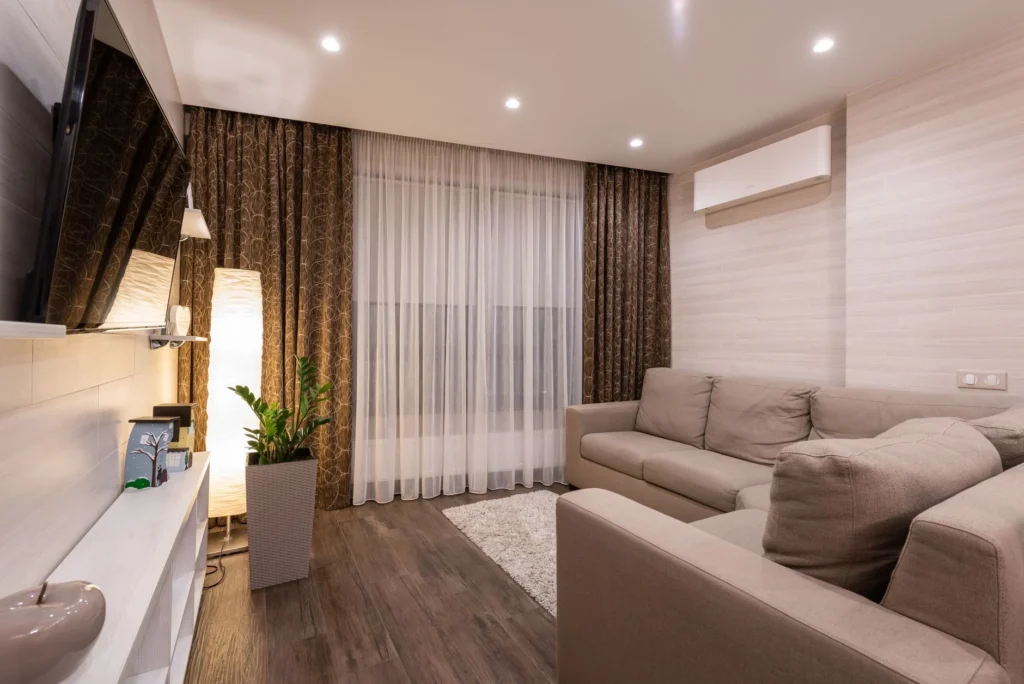 A stylish and cozy living room featuring a sofa, wooden flooring, and soft lighting.
