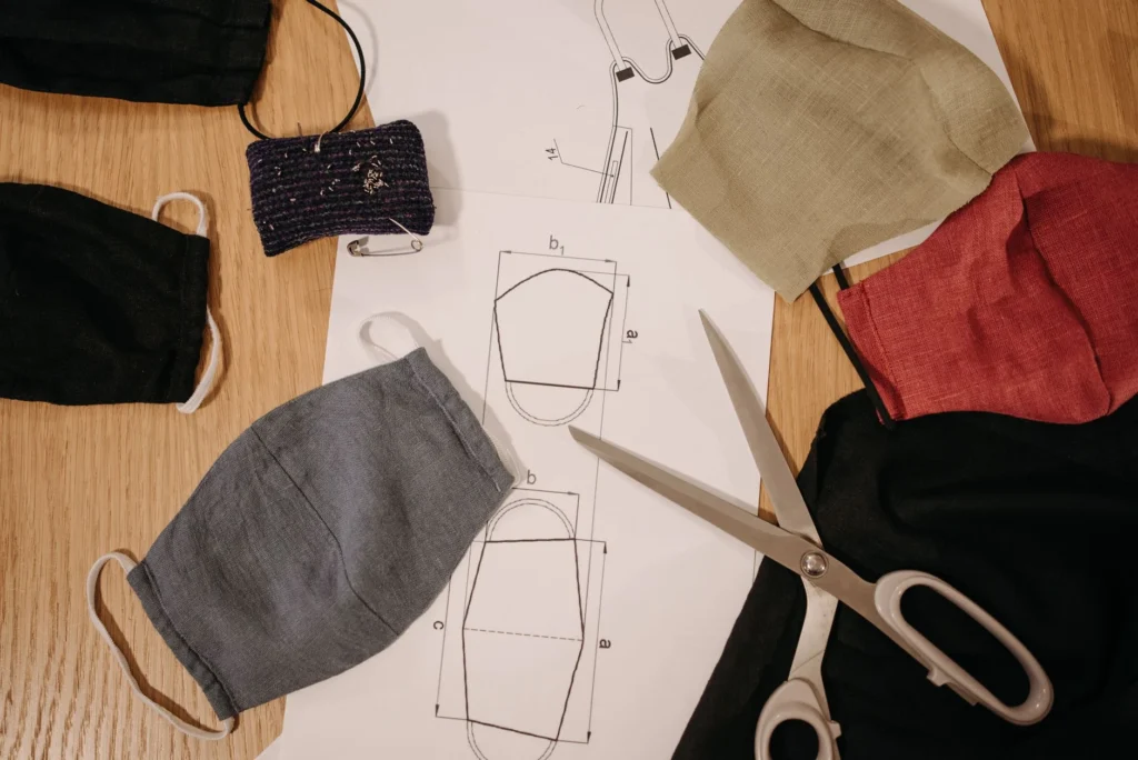 Creative setup of handmade face masks with design sketches and sewing tools.