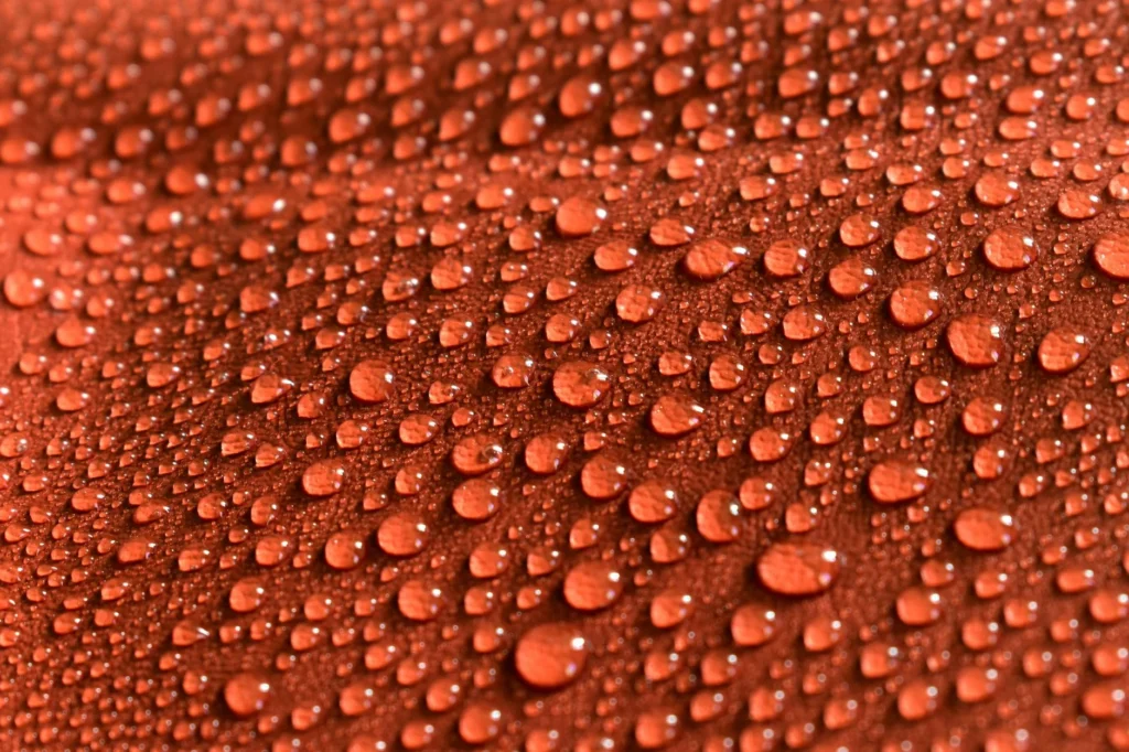 Detailed close-up photo of water droplets on an orange patterned surface, showcasing texture and pattern.